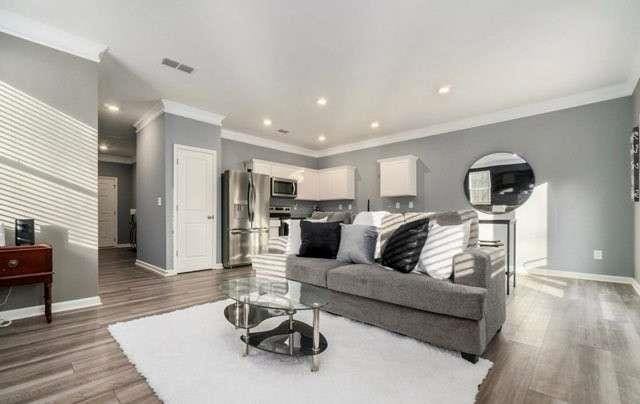 living room featuring visible vents, baseboards, wood finished floors, and recessed lighting