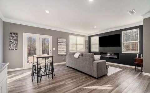 living room with ornamental molding, wood finished floors, visible vents, and baseboards