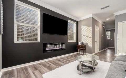 living area with ornamental molding, a glass covered fireplace, visible vents, and baseboards