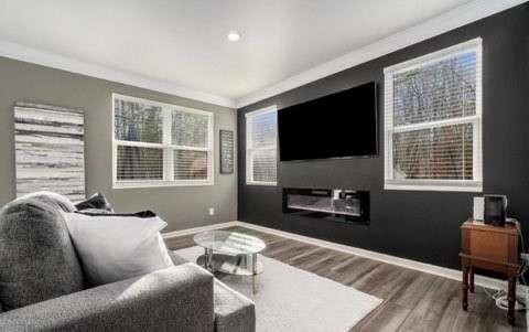 living area with ornamental molding, a fireplace, baseboards, and wood finished floors