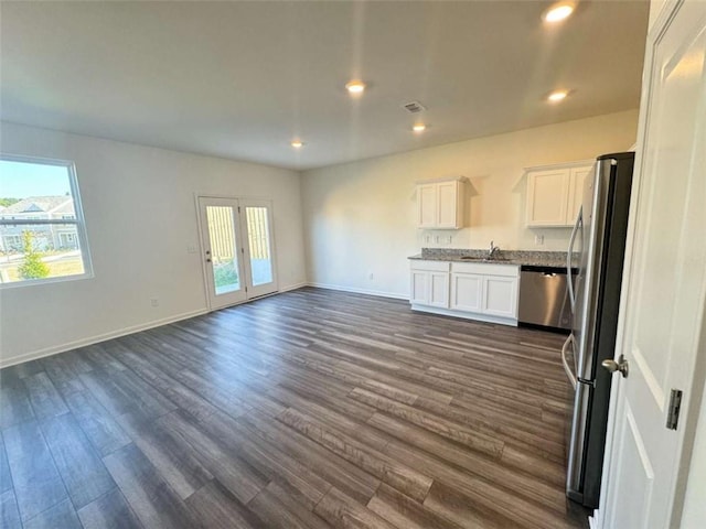 kitchen featuring open floor plan, appliances with stainless steel finishes, plenty of natural light, and white cabinetry