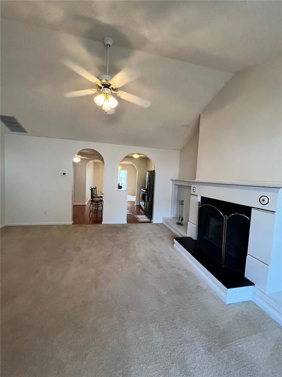 unfurnished living room with lofted ceiling, carpet flooring, and ceiling fan