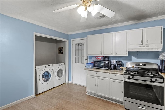 kitchen featuring appliances with stainless steel finishes, light wood-type flooring, ornamental molding, washing machine and dryer, and white cabinetry