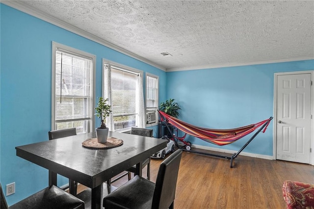 dining room with a textured ceiling, hardwood / wood-style flooring, plenty of natural light, and ornamental molding