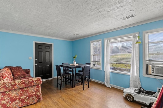 dining area with hardwood / wood-style flooring, ornamental molding, and a textured ceiling