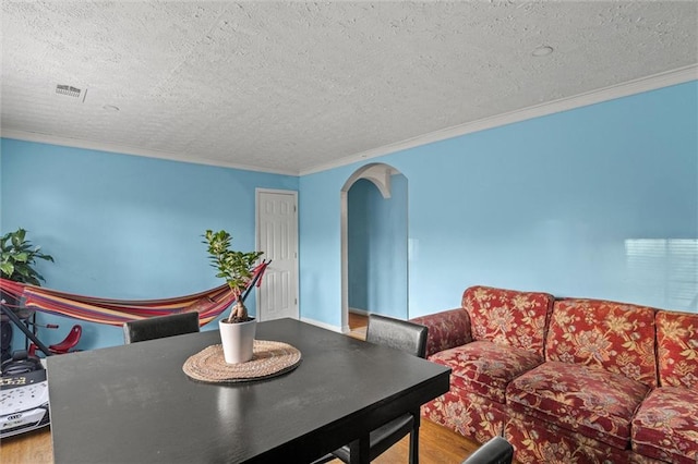 dining space featuring hardwood / wood-style floors, a textured ceiling, and crown molding