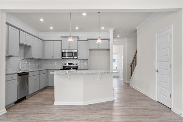 kitchen featuring light wood-style flooring, appliances with stainless steel finishes, gray cabinetry, and a sink