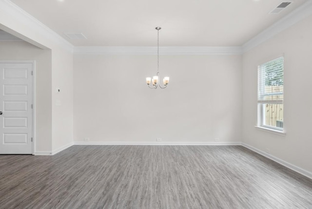 empty room featuring visible vents, wood finished floors, a notable chandelier, and ornamental molding