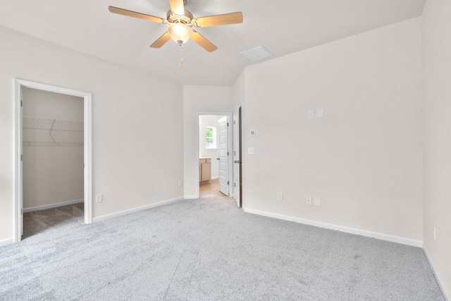 unfurnished bedroom featuring carpet flooring, ceiling fan, a walk in closet, and baseboards