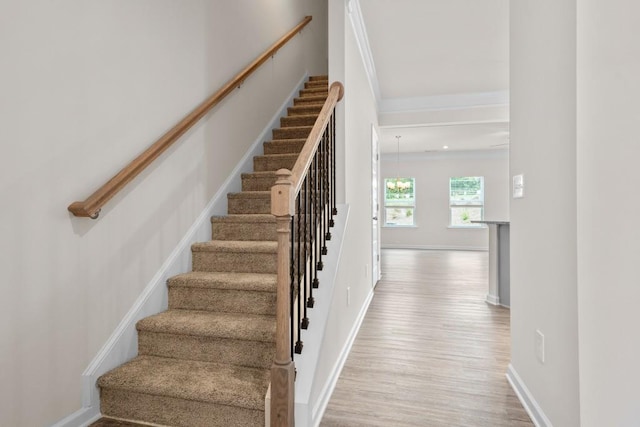 stairway featuring wood finished floors, baseboards, and ornamental molding