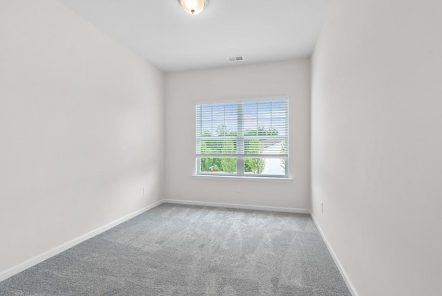 carpeted spare room featuring visible vents and baseboards