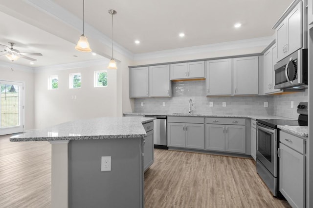 kitchen with gray cabinets, appliances with stainless steel finishes, a kitchen island, and a sink