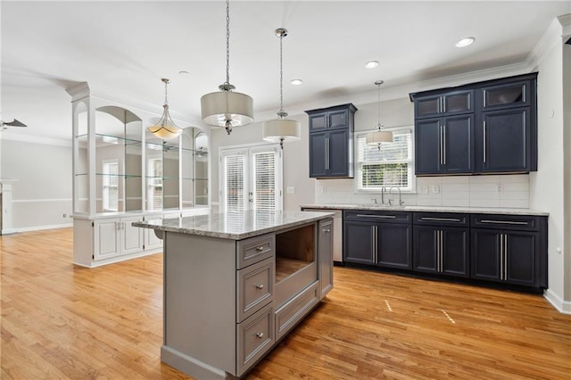 1755 Pinetree Pass Ln SW, Lilburn, GA 30047 - kitchen with decorative light fixtures, a sink, light wood-style floors, crown molding, and backsplash