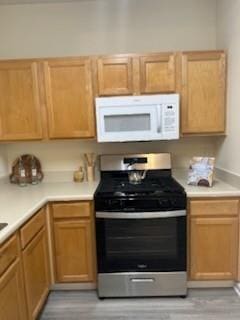 2991 Greyhawk Ln, Cumming, GA 30040 - kitchen with white microwave, gas stove, light countertops, and light wood-type flooring