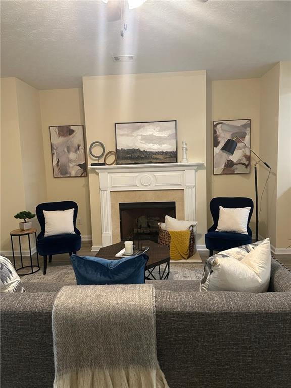 2991 Greyhawk Ln, Cumming, GA 30040 - living room with baseboards, a fireplace, a textured ceiling, a ceiling fan, and visible vents