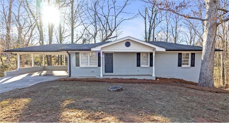 ranch-style home featuring driveway, brick siding, and a carport