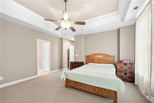 bedroom featuring ceiling fan, light carpet, and a tray ceiling