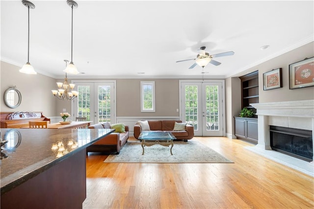 living room featuring built in shelves, crown molding, french doors, and light hardwood / wood-style floors