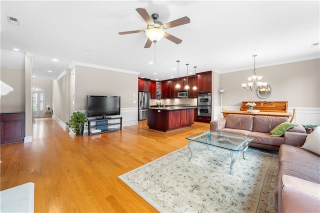 living room with ceiling fan with notable chandelier, light hardwood / wood-style flooring, and crown molding