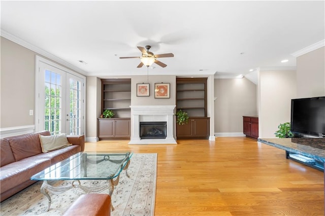 living room with french doors, ceiling fan, built in features, ornamental molding, and wood-type flooring