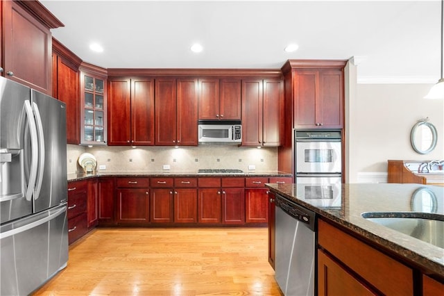 kitchen with light hardwood / wood-style floors, crown molding, appliances with stainless steel finishes, and tasteful backsplash