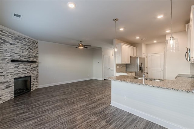 kitchen featuring sink, appliances with stainless steel finishes, light stone countertops, white cabinets, and decorative light fixtures