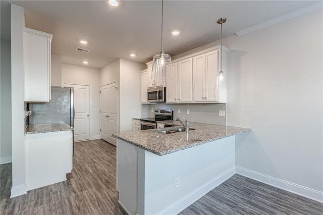 kitchen with appliances with stainless steel finishes, decorative light fixtures, sink, white cabinets, and kitchen peninsula