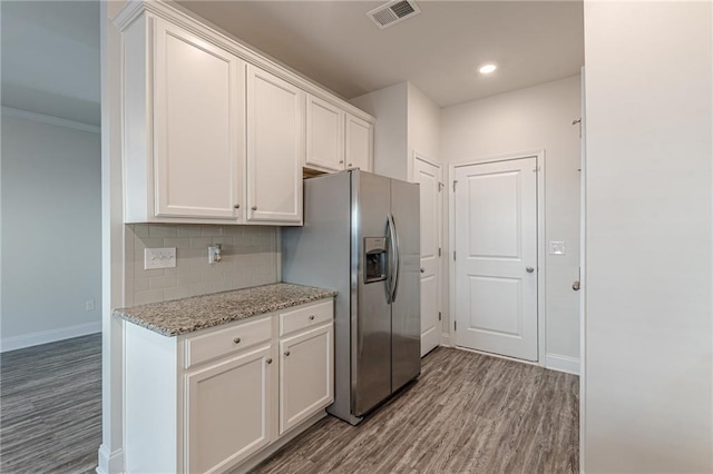 kitchen with white cabinetry, decorative backsplash, light stone counters, stainless steel refrigerator with ice dispenser, and light wood-type flooring