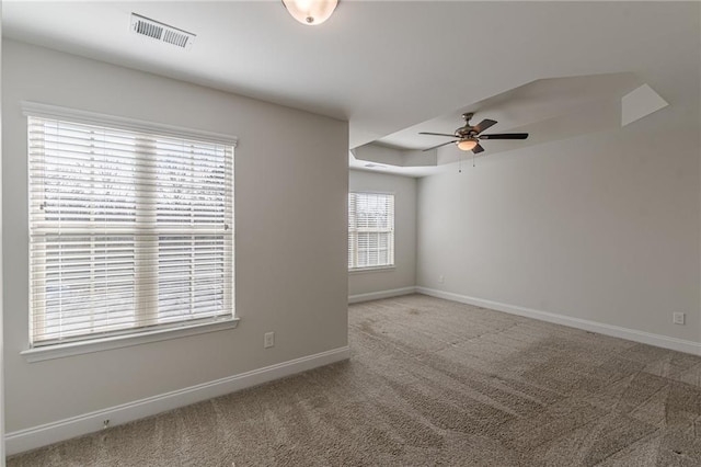 empty room featuring carpet floors, a raised ceiling, and ceiling fan