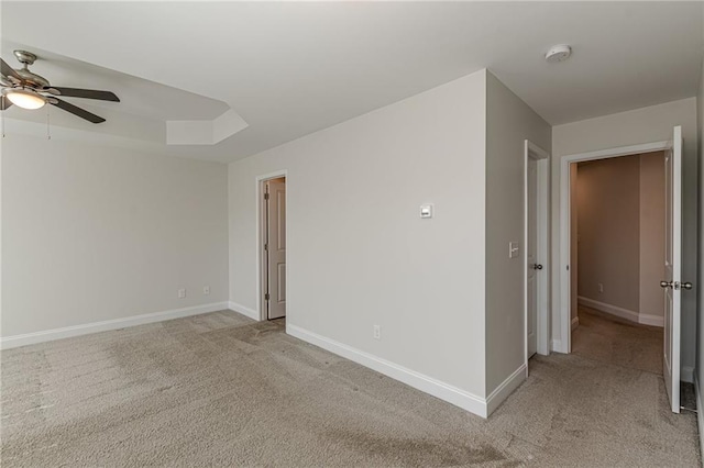 carpeted spare room with ceiling fan and a tray ceiling