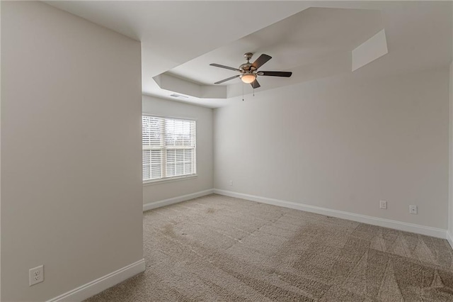 spare room featuring ceiling fan, light colored carpet, and a tray ceiling