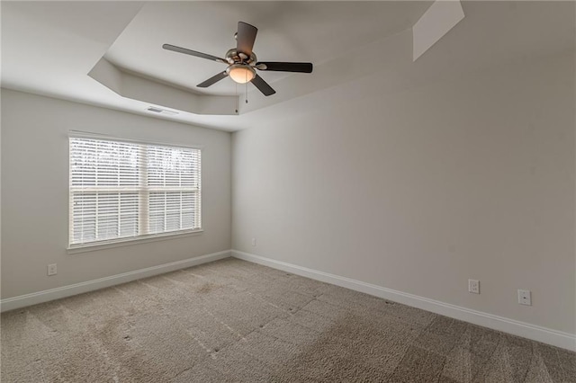 carpeted spare room with a tray ceiling and ceiling fan