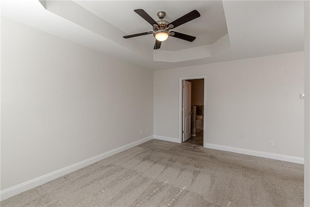 carpeted spare room featuring ceiling fan and a tray ceiling