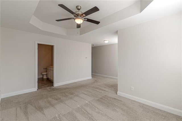 carpeted spare room featuring a raised ceiling and ceiling fan