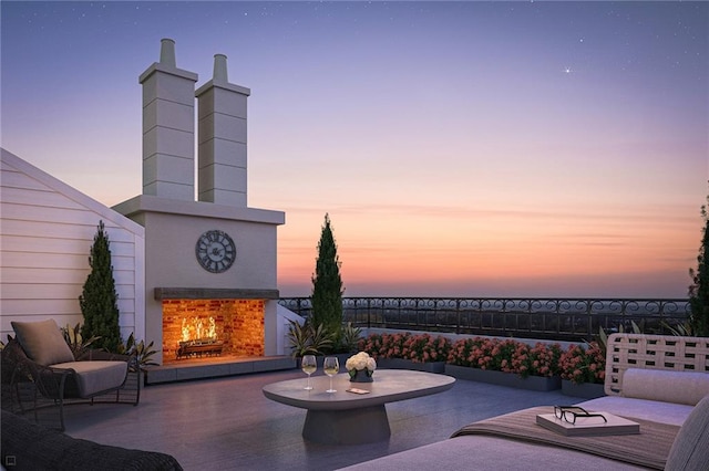 patio terrace at dusk featuring exterior fireplace