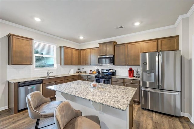 kitchen with sink, appliances with stainless steel finishes, a center island, light stone countertops, and dark hardwood / wood-style flooring