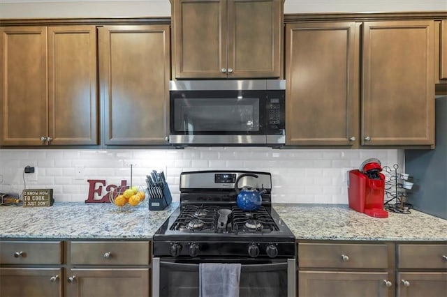 kitchen with light stone counters, decorative backsplash, and appliances with stainless steel finishes