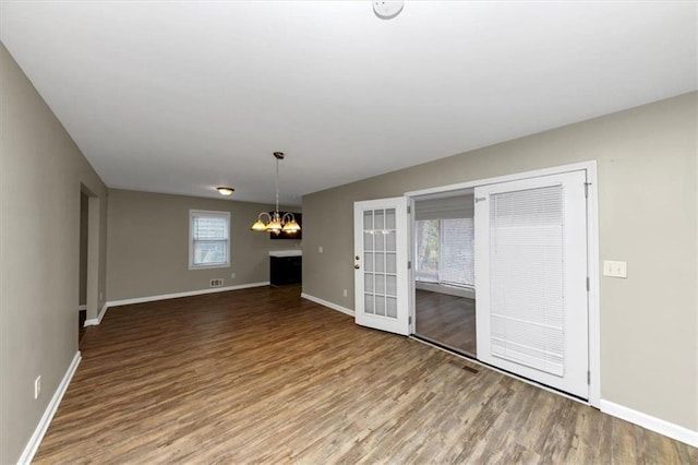 unfurnished living room featuring wood-type flooring and an inviting chandelier