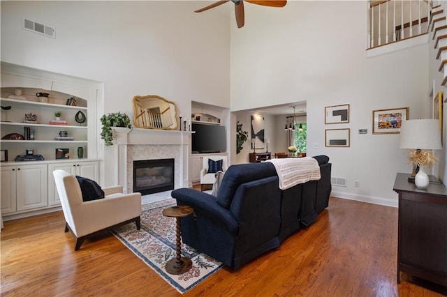 1360 Edmund Ct NE, Atlanta, GA 30306 - living room featuring a high ceiling, a ceiling fan, light wood-style flooring, a glass covered fireplace, and built in features