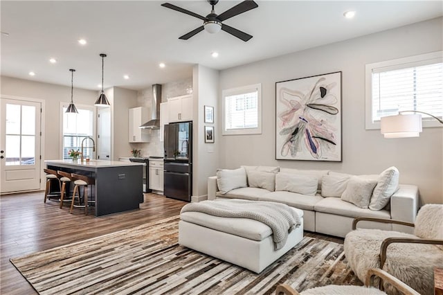 living room with wood finished floors, a ceiling fan, and recessed lighting