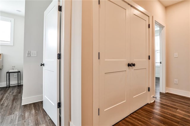 hall with dark wood-style flooring and baseboards