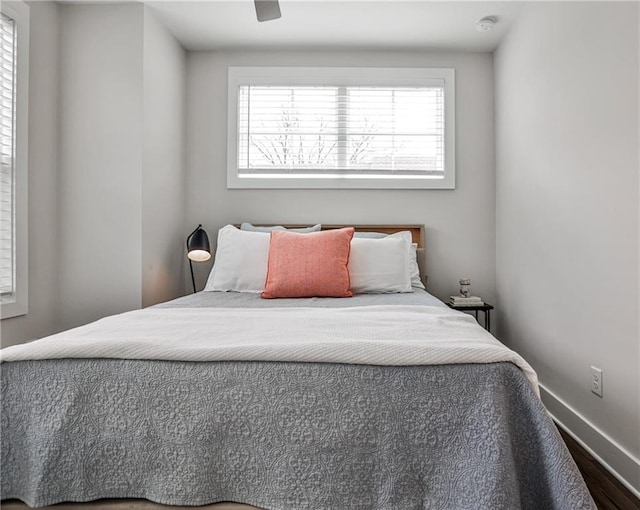 bedroom with ceiling fan, wood finished floors, and baseboards