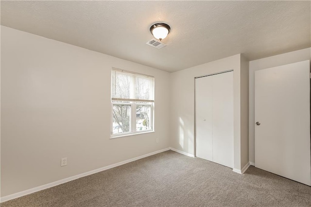 unfurnished bedroom with a textured ceiling, a closet, and carpet