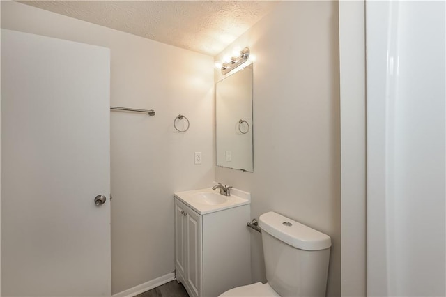 bathroom featuring toilet, a textured ceiling, and vanity