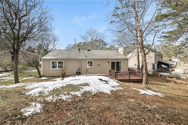 snow covered back of property with a wooden deck