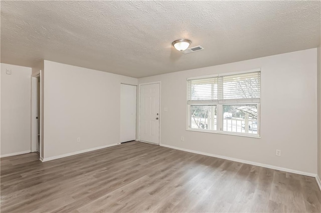 spare room featuring hardwood / wood-style floors and a textured ceiling