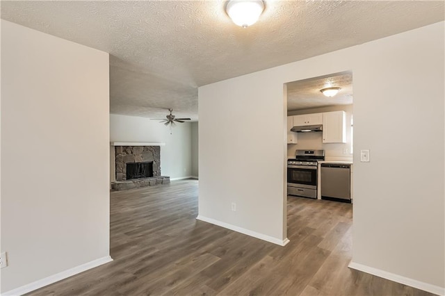 unfurnished living room featuring wood-type flooring, a textured ceiling, ceiling fan, and a fireplace