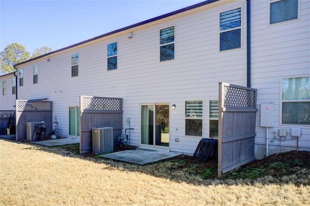 rear view of property featuring central air condition unit, a lawn, and a patio