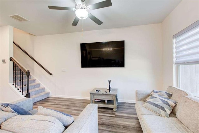 living area featuring visible vents, stairway, a ceiling fan, wood finished floors, and baseboards