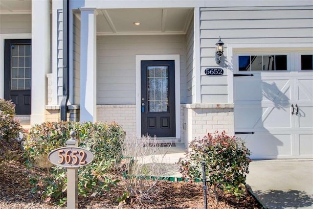 doorway to property featuring a garage and brick siding